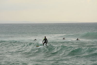 People in sea against clear sky