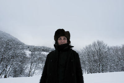 Woman standing against bare trees during winter