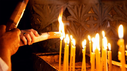 Close-up of hand holding lit candles in temple