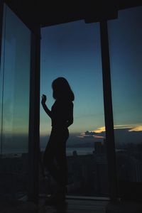 Side view of silhouette boy standing against window