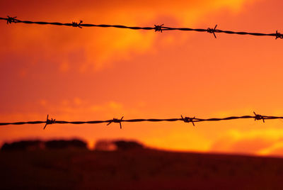 Close-up of silhouette barbed wire against sky