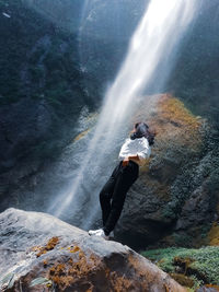 Man surfing on rock in sea