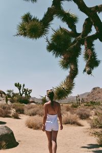 Rear view of woman walking at beach against sky