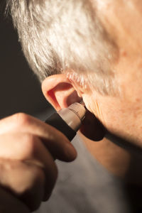 Cropped image of man holding thermometer in ear