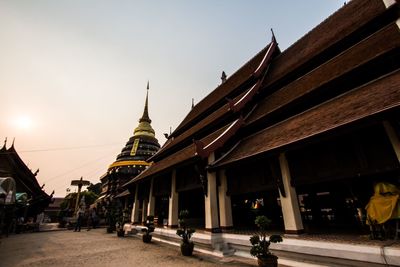 People walking outside temple against sky in city