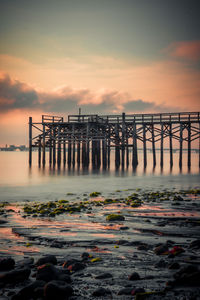 Pier on sea against sky during sunset