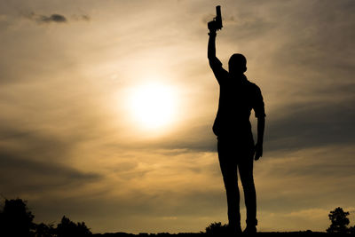 Low angle view of silhouette man standing against sky during sunset