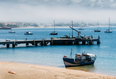 Boats moored at harbor against sky