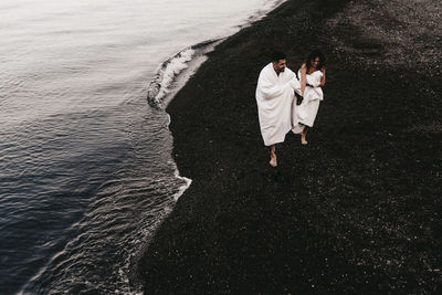 Rear view of couple walking in water