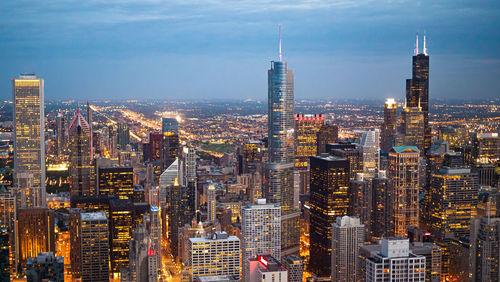 Aerial view of city lit up against sky