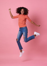 Portrait of woman jumping against gray background