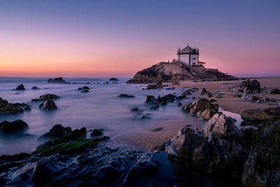 Rocks in calm sea against clear sky