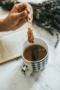 Midsection of person holding tea cup on table