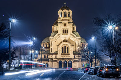 Illuminated street amidst buildings at night