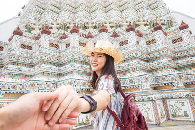 Cropped image of man holding hands with girlfriend standing against temple
