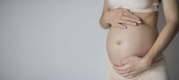 Midsection of woman touching hair against white background