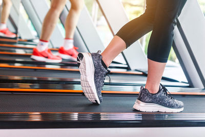 Low section of women running on treadmill in gym