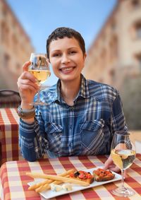 Portrait of a smiling young man drinking glass on table