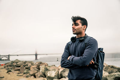 Young man standing on rock against sea