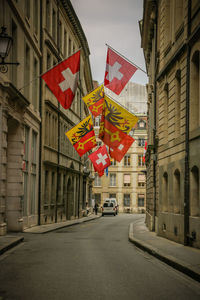 Road amidst buildings in geneva with swiss flags