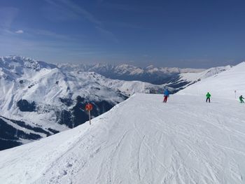 People skiing on snowcapped mountain against sky