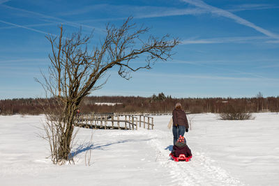 Rear view of woman on snow covered field against sky