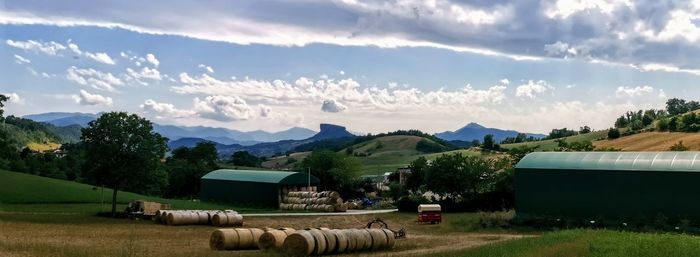 Panoramic shot of hay bales on field against sky