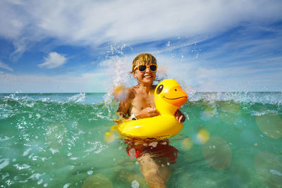 Young woman swimming in sea against sky