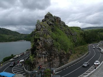 Vehicles on road by mountain against sky