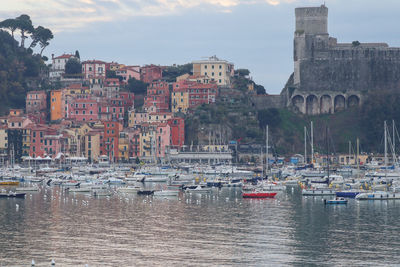 Sailboats moored in harbor against buildings in city