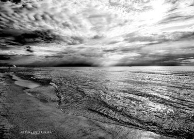 Scenic view of beach against cloudy sky