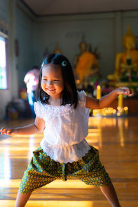 Cute girl standing against buddha statue in temple