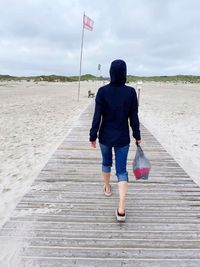 Rear view of woman walking on footpath against sky