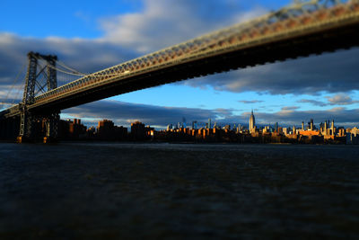 Bridge over river in city against cloudy sky