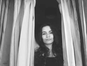 Portrait of smiling young woman looking through window