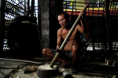 Portrait of shirtless man working in machine