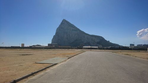 Road by mountain against blue sky