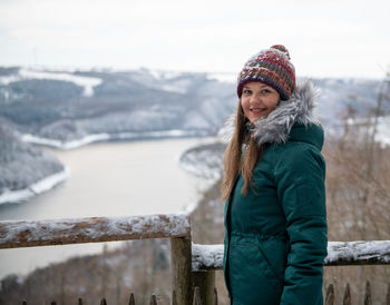 Portrait of smiling young woman standing by railing