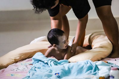 Midsection of mother and son on bed