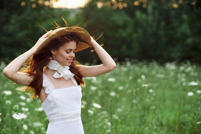 Portrait of young woman standing against trees