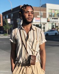 Young man looking away while standing on road in city