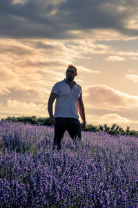 Side view of man standing on field against sky during sunset