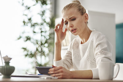 Thoughtful businesswoman using calculator at desk in office