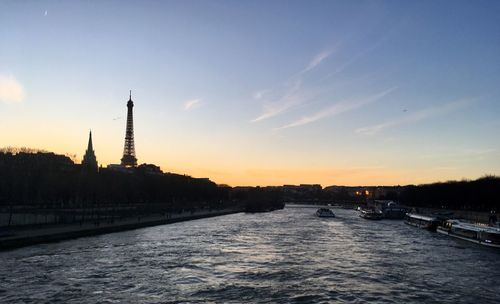 View of river and buildings against sky during sunset