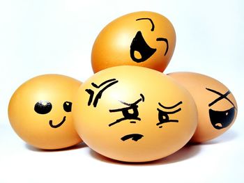 Close-up of anthropomorphic faces on eggs over white background