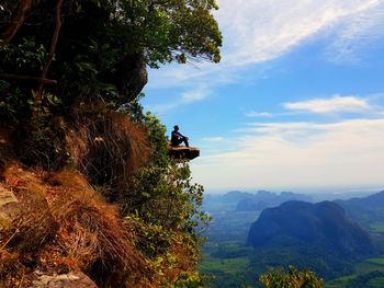 People sitting on rock against sky