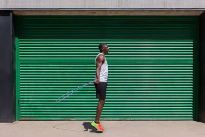 Focused african american male athlete jumping rope during cardio workout on sunny day in city