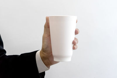 Hand holding coffee cup against white background