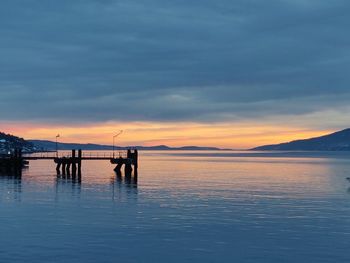 Silhouette pier over sea against sky during sunset