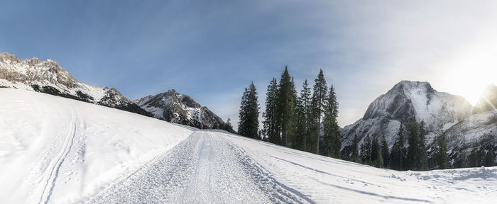 Snow covered road by mountain against sky